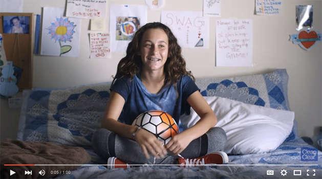 teenage girl sitting on a bed with a soccer ball