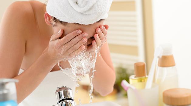 girl with a towel on her head washing face